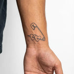 Tatuaggio semi-permanente INKON Safety Pin & Hearts applicato su un uomo – design 2 x 2 in (5x5cm), aspetto realistico dell'inchiostro, dura 10 giorni