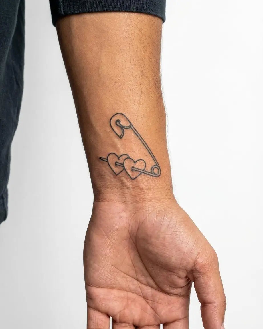 Tatuaggio semi-permanente INKON Safety Pin & Hearts applicato su un uomo – design 2 x 2 in (5x5cm), aspetto realistico dell'inchiostro, dura 10 giorni